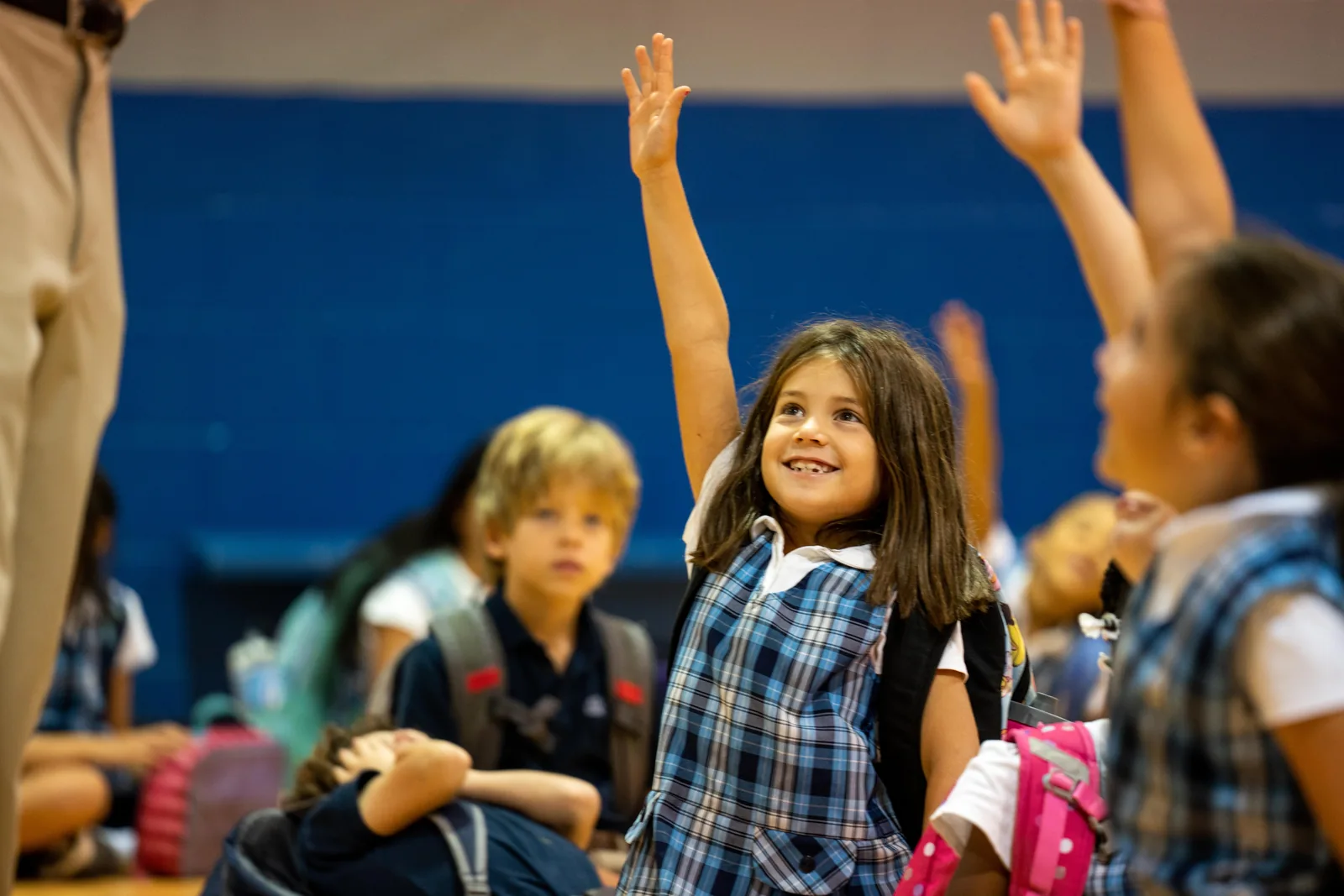 Smiling student raising her hand among other children at ACA